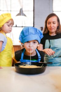 Children and adult cooking in kitchen, enjoying and learning together.