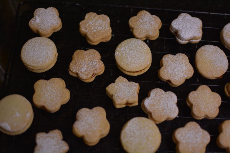 A batch of freshly baked shortbread cookies cooling on a rack, dusted with powdered sugar.